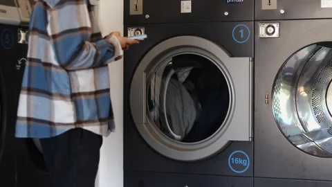 Public laundry washing machine with clothes inside. drying things. young man Stock Footage 231001017