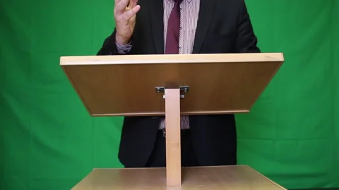 Public speaker behind the podium. A man in a suit and tie says something and  Stock Footage 221311833