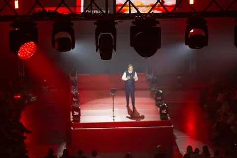 Public speaker on illuminated stage under red lights during live event with 写真素材