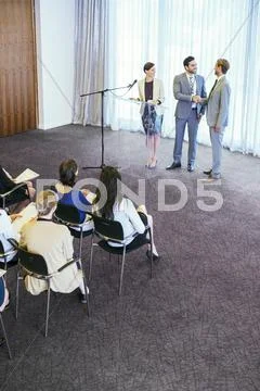 Public speakers shaking their hands on stage during conference Stock Photos