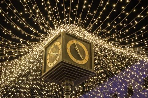 Public square clock glowing under canopy of golden lights during GDLuz Stock Photos