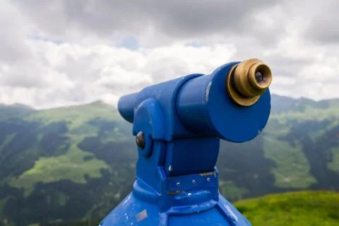 Public telescope arrayed against mountain range Alps in Austria, cloudy Стоковые фото