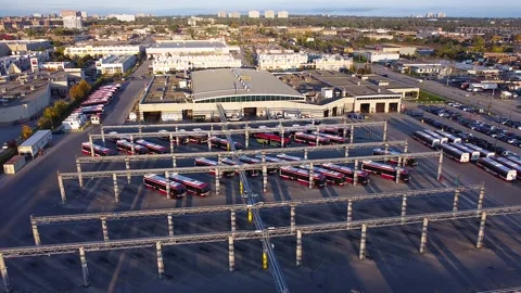 Public transit buses parked at electric charging stations outside large Stock Footage 237682165