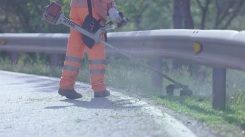 Public worker dressed in protective clothing brushing and mowing. Stock Footage 166890835