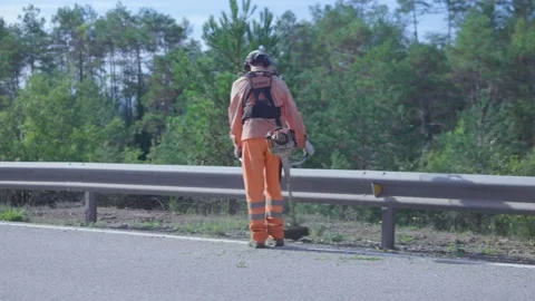 Public worker dressed in protective clothing brushing and mowing. Stock Footage 166890859