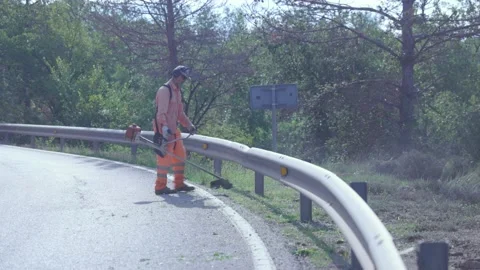 Public worker dressed in protective clothing brushing and mowing. Stock Footage 166890860
