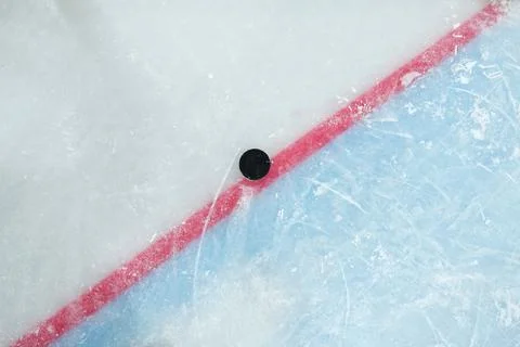 Puck lying on red line dividing play space and zone of net on large ice rink Stock Photos