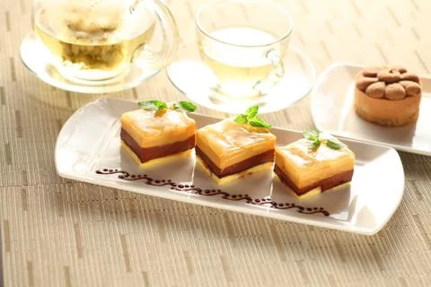 Pudding cake with mint leaves on white plate with tea Stock Photos