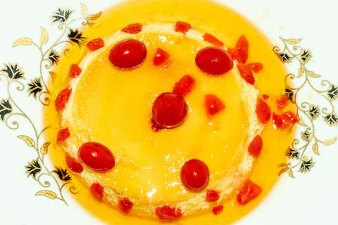 Pudding made with egg milk and sugar and served topped with red cherry fruit Stock Photos