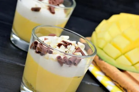 Pudding of mango fruit in a glasses jar and mango cubes on a wooden table Stock-Fotos