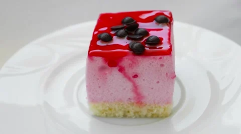 Pudding with strawberry jam and chocolate decoration, rotating on a white plate Stock Footage 54338138