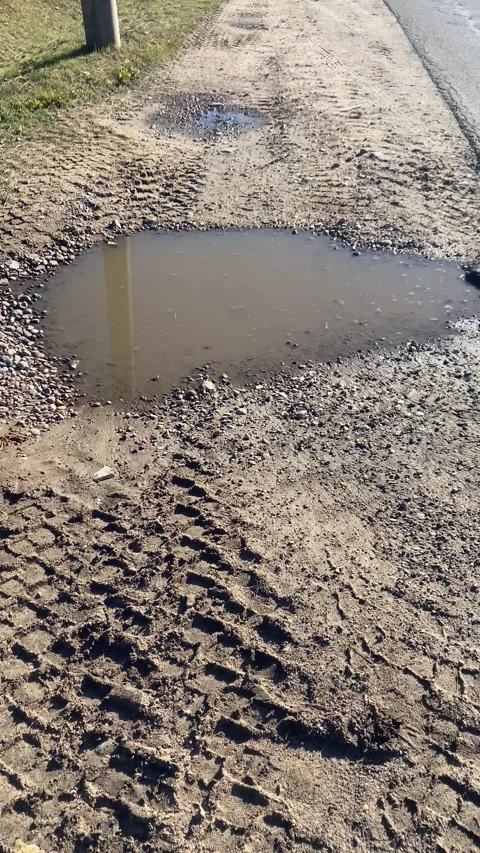 A puddle along the road. Puddle on the sand. Vertical video Stock Footage 287937725