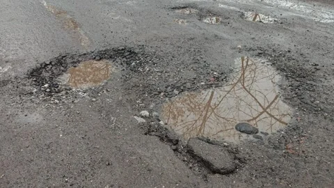 Puddle in broken road with deep pothole after rain Stock Footage 340030345