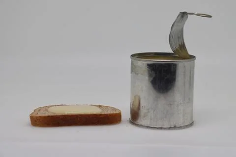 Puddle of condensed milk flows from levitating jar, can opener, black bread Stock Photos