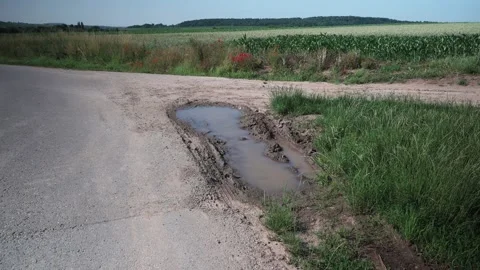 Puddle on a dirt road between fields Stock Footage 141468007