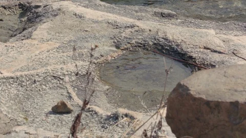 A puddle formed in the side of a rock with waves in the background in slow motio Stock Footage 88644157
