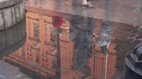 In a puddle on the pavement, an old building and passers-by are reflected. Stock-Footage 93277871