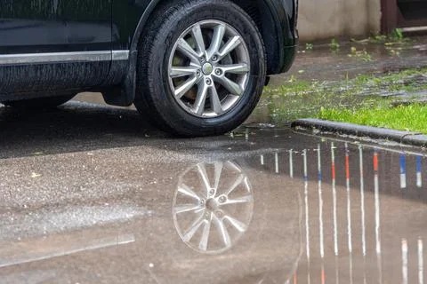 Puddle on the pavement with a reflection of the car wheel, closeup Stock Photos