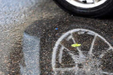 Puddle on the pavement with a reflection of the car wheel, closeup Stock Photos