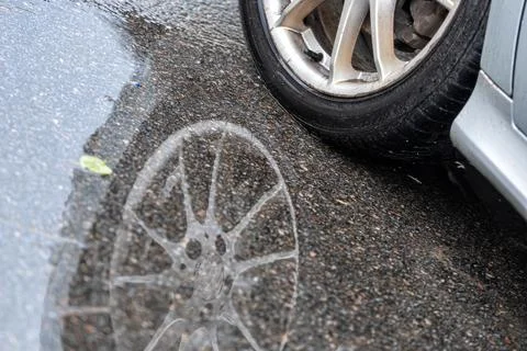 Puddle on the pavement with a reflection of the car wheel, closeup Stock Photos