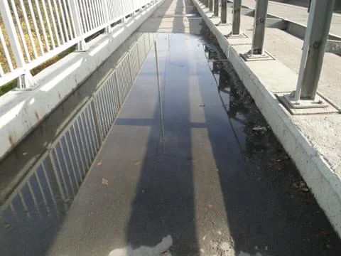 Puddle on the pedestrian bridge with mirror reflection Stock Photos