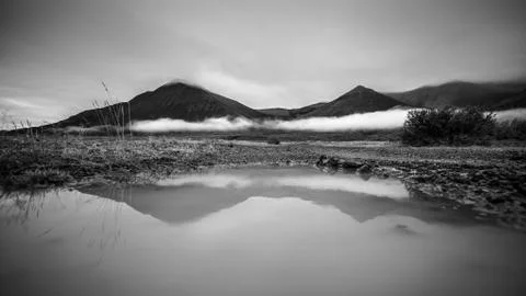 Puddle of rain with reflection in the front. Mountain with fog in the backg.. Stock-Fotos