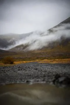 Puddle of rain with reflection in the front. Mountain with fog in the backg.. Stock Photos