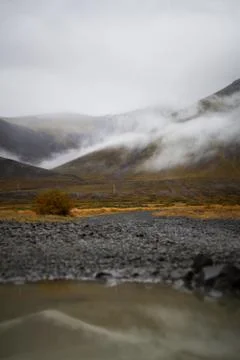 Puddle of rain with reflection in the front. Mountain with fog in the backg.. Stock Photos
