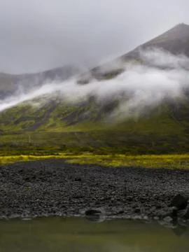 Puddle of rain with reflection in the front. Mountain with fog in the backg.. Stock Photos