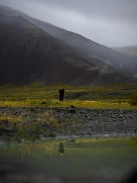Puddle of rain with reflection in the front. Mountain with fog in the backg.. Stock Photos