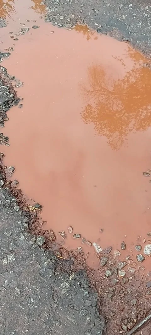 A puddle of red-rust color on the road after rain. A puddle of red-rusty color Stock Footage 318217241