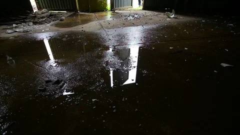 Puddle reflection of a man entering dark abandoned building. Video footage. Stock Footage 107651212