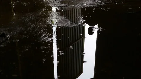 Puddle reflection of a man entering dark abandoned building. Video footage. Stock Footage 107651321