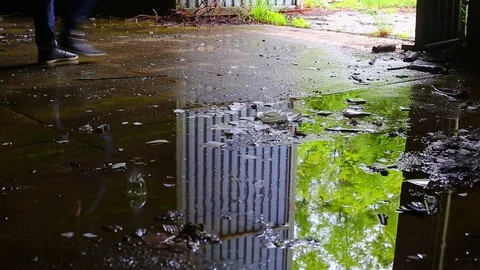 Puddle reflection of a man leaving dark abandoned building. Video footage. Stock Footage 107650010