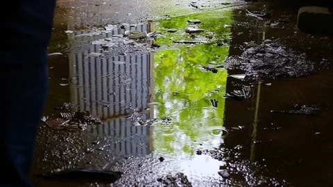 Puddle reflection of a man leaving dark abandoned building. Video footage. Stock Footage 107651363