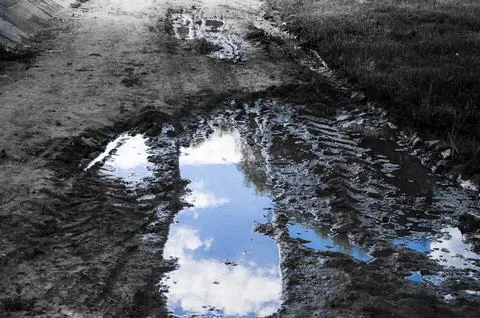 Puddle with reflection of the sky and clouds in black and white Stock Photos