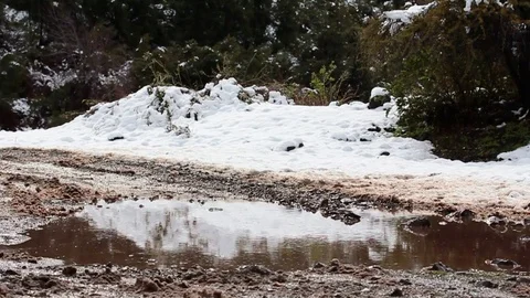 Puddle on snowy hill road Stock Footage 77052282