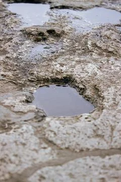 Puddle on uneven ground surface after rain close up Stock Photos