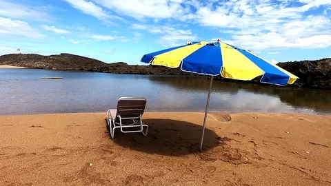 Puerto Nuevo Beach, Tracking Shot of a Reclining Beach Chair under an Umbrella Stock Footage 129206043