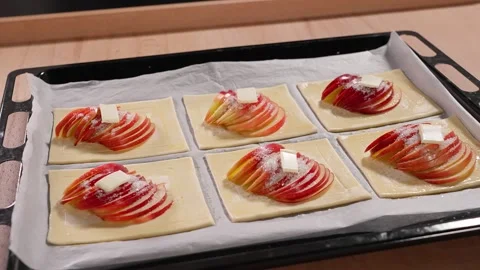Puff pastries with red apple slices sprinkled with sugar and a piece of butter Stock Footage 267010764