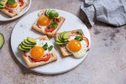 Puff pastry with fried egg, pepper and avocado Stock Photos