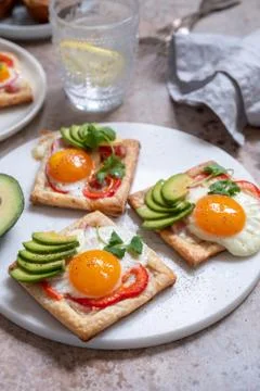 Puff pastry with fried egg, pepper and avocado Stock Photos