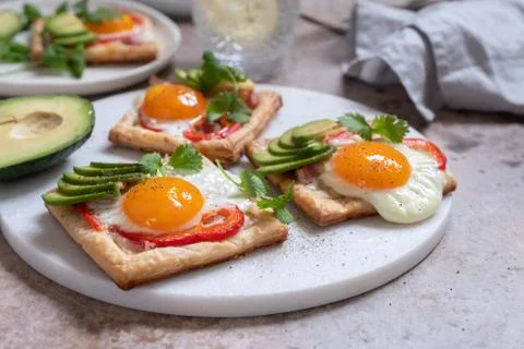 Puff pastry with fried egg, pepper and avocado Stock Photos