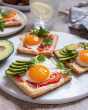 Puff pastry with fried egg, pepper and avocado Stock Photos