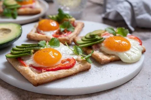 Puff pastry with fried egg, pepper and avocado Stock Photos