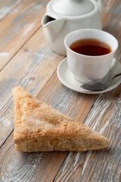 Puff pastry triangle with sugar as a simple treat to a cup of black tea Stock Photos