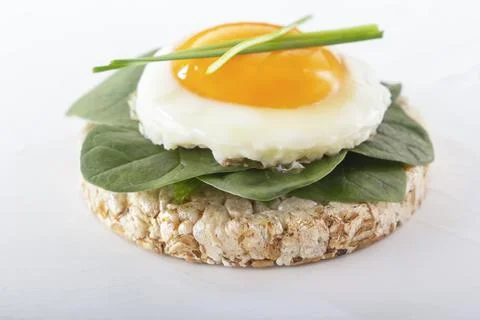 Puffed exploded wheat grains with fried egg and spinach leaves Foto stock