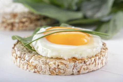 Puffed exploded wheat grains with fried egg and spinach leaves Foto stock
