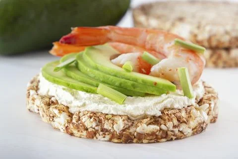Puffed exploded wheat grains with shrimps and avocado slices on soft cheese Foto stock