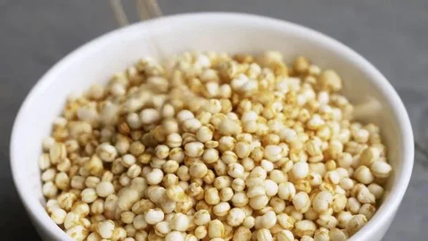 Puffed quinoa falling into a small bowl Stock Footage 69166523